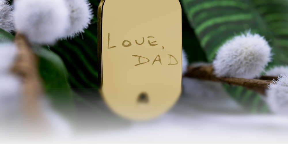A gold memory tag with "Love Dad" engraved on the face.