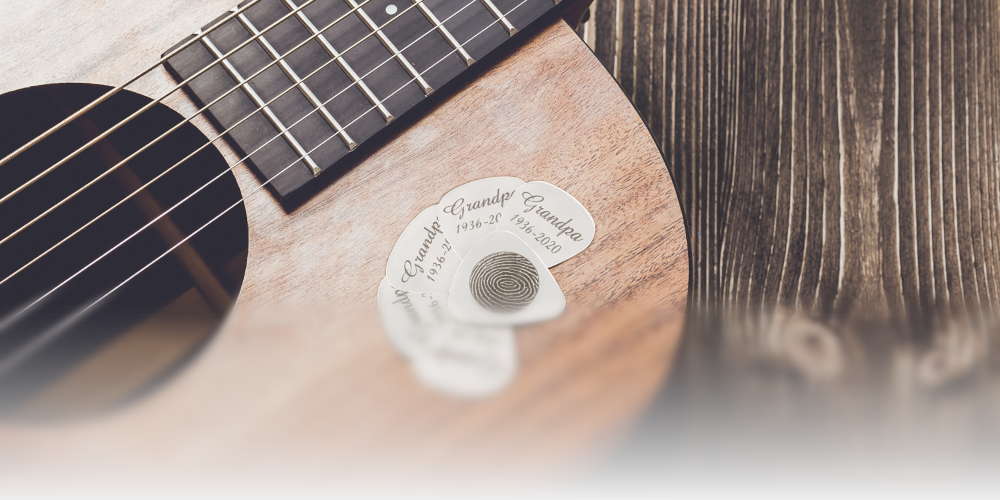 A six pack of stainless steel guitar picks laying on an acoustic guitar.