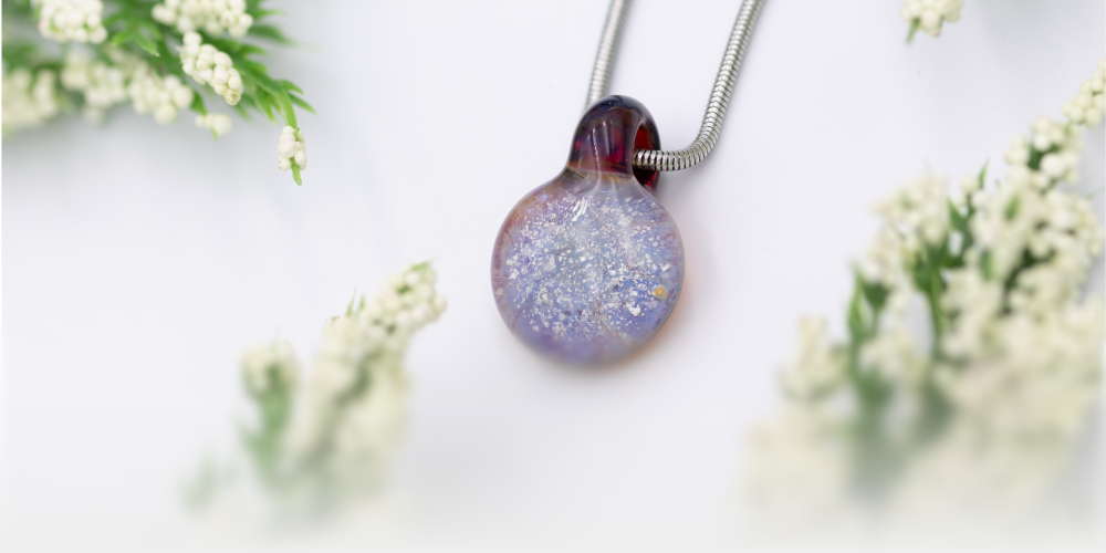 A Serenity Circle Pendant laying flat with greenery surrounding.