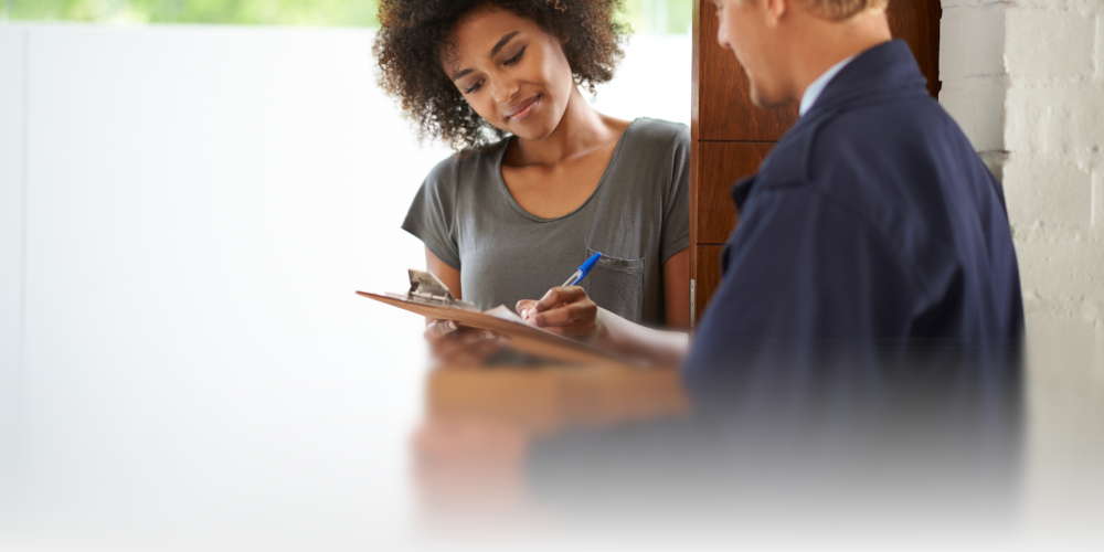 A woman signing for a received ordered package to her house.